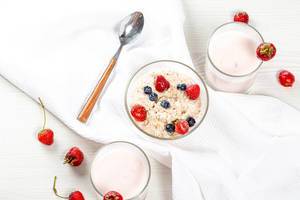 Frühstücksflocken mit Erdbeeren und Heidelbeeren und Joghurt auf dem weißen Tisch, aus der Sicht von oben