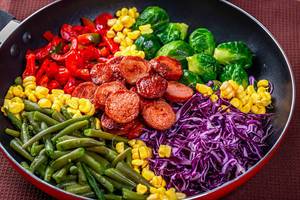 Frying pan with vegetables and sausages