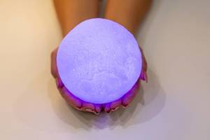 Full purple moon night light in the hands of a woman