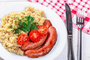 Funny lunch with porridge, sausages, tomatoes and herbs