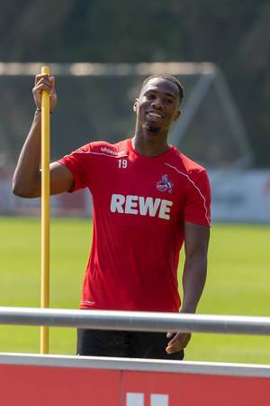 Fußballer Kingsley Ehizibue mit Trainingsutensilien in der Hand, lacht fröhlich in die Kamera