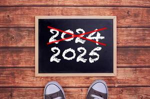 Füße vor einer Jahreszahltafel symbolisieren den Übergang und Eintritt in das Jahr 2025