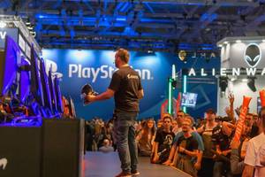 Gamescom Event: Man on stage handing out merchandise shirts to a crowd