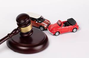 Gavel and two toy cars on white background