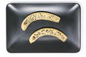 Gebackene Bananen mit geschmolzenen Schokoraspeln auf schwarzem Teller