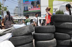 Gebrauchte, abgefahrene Reifen auf der Straße und Passanten im Hintergrund