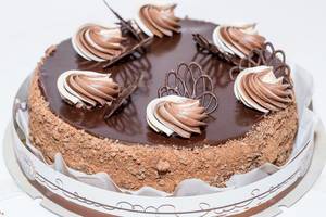 Geburtstagskuchen mit Schokoladenglasur, Nüssen und Sahnedekoration vor weißem Hintergrund