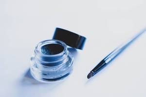 Gel eyeliner container with brush beside it