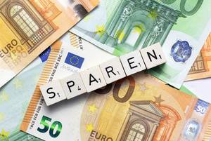 Geld Sparen  - Schriftzug mit Würfeln auf Euroscheinen