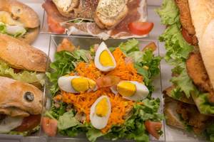 Gemischter Salat mit Eiern und Rohschinken mit Brot zwischen Schnitzelbroten
