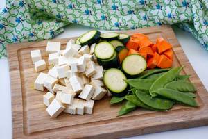 Gemüse und Tofu auf einem Küchenbrett