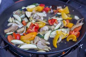 Gemüsewok auf einer Gaskochplatte, mit Paprika, Zucchini, Blumenkohl und Aubergine