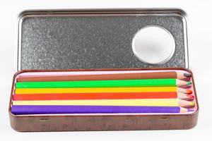 Geöffnete Metallbox mit farbigen Holzmalstiften vor weißem Hintergrund