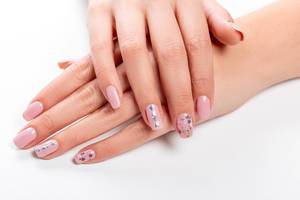 Gepflegte Frauenhände mit rosa lackierten Fingernägeln auf weißem Hintergrund Nahaufnahme