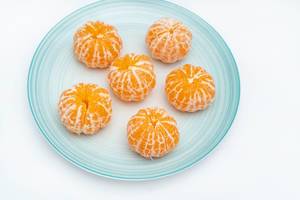 Geschälte Mandarinen auf einem blauen Teller serviert