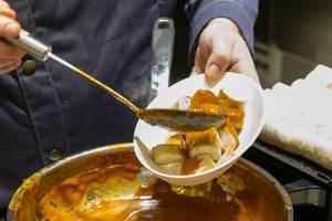 Geschnittene Currywurst wird mit Currysauce übergoßen