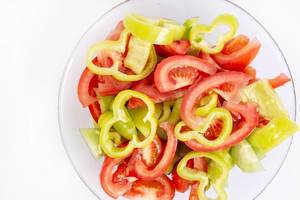 Geschnittene Tomatenscheiben & grüne und rote Paprika, auf einem Salatteller