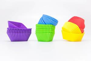 Gestapelte Cupcakeförmchen aus Gummi, in verschiedenen Farben, vor weißem Hintergrund