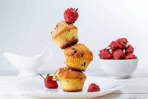 Gestapelte Muffins mit Schokostückchen und frischen Erdbeeren