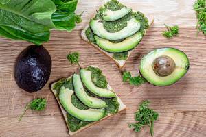 Gesunde vegetarische Ernährung: Sandwich mit grünen Kräutern und Avocado auf Holzhintergrund Top-view