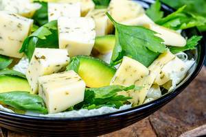 Gesunder Diät Salat mit würzigen Käsewürfeln, Avocado-Scheiben und Petersilie Nahaufnahme