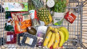 Gesunder Einkaufswagen mit veganen Lebensmitteln, frischem Obst, Gemüse und Kokosmilch