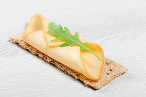 Gesundes Abonett-Sandwich mit Käse und frischer Rucola auf einem Holztisch