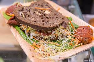 Gesundes vegetarisches Sandwich mit Tomatenpuree, Karotte und verschiedenen Keimen auf Salat-Bett