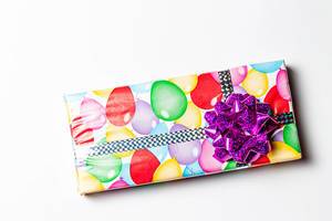 Gift with a bow in multicolored paper on a white background (Flip 2020)