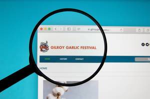 Gilroy Garlic Festival website on a computer screen with a magnifying glass