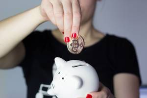 Girl saving bitcoin in piggy bank