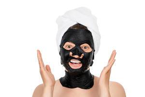Girl with a black mask on her face to cleanse skin pores. The concept of care and beauty