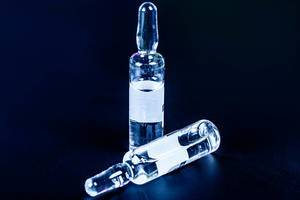 Glass ampoules with liquid medicine on a black background (Flip 2020)
