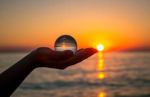 Glass ball in girls hand during sunset
