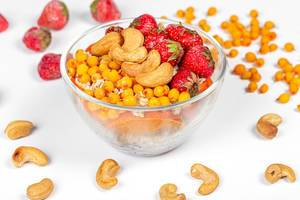 Glass bowl with oatmeal, strawberries, sea buckthorn berries and cashew nuts (Flip 2020)