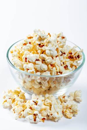 Glass bowl with popcorn on white background