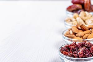 Glass bowls with nuts and dried fruits on white wooden background with free space (Flip 2019)