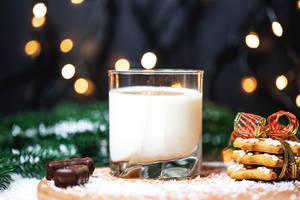 Glass of milk with ginger cookies on Christmas background