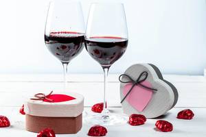 Glasses of red wine with gifts and chocolates