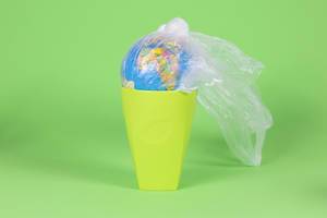 Globe in plastic bag in trash can - concept on the plastic issue