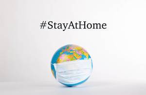 Globe with medical mask and #StayAtHome text on white background