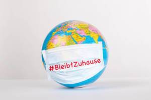 Globe with medical mask on white background and #BleibtZuhause text