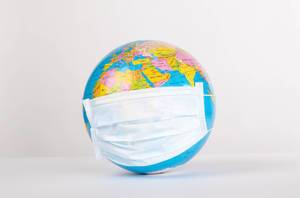 Globe with medical mask on white background