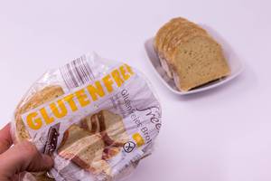 Glutenfreies Brot in Verpackung und Brotscheiben in Schale im Hintergrund
