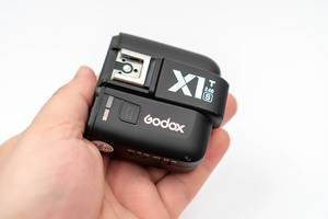 Godox-X1-flash-controller-in-the-hand-above-white-background.jpg