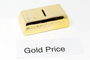Gold bars and paper with the words GOLD PRICE in front of white background