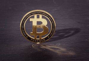 Golden Bitcoin with reflection on a black background