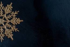Golden snowflake on black background with free space