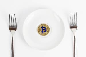 Goldene Bitcoin Münze im weißen Teller