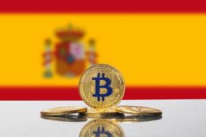 Goldene Bitcoins platziert vor der Flagge südeuropäischen Landes Spanien